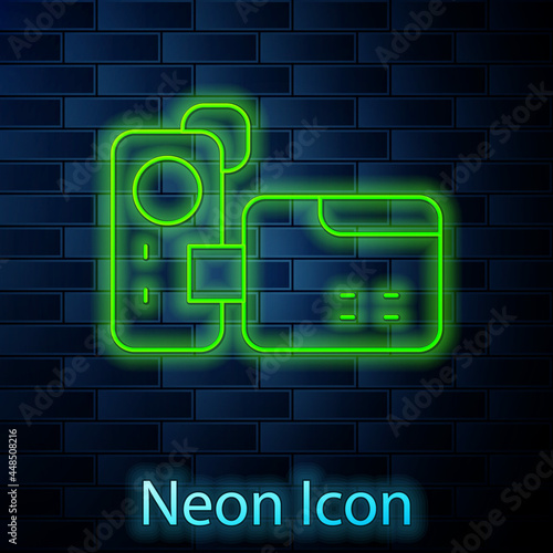 Glowing neon line Cinema camera icon isolated on brick wall background. Video camera. Movie sign. Film projector. Vector