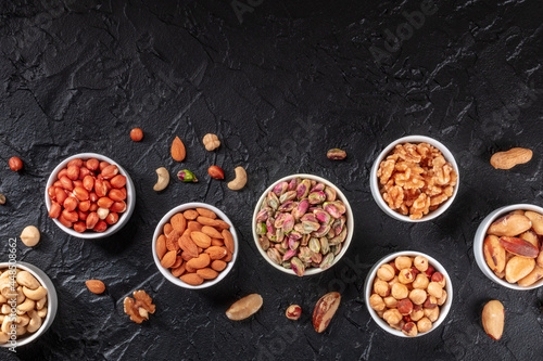 Nuts variety with copy space, shot from above on a black slate background. Healthy vegan snack