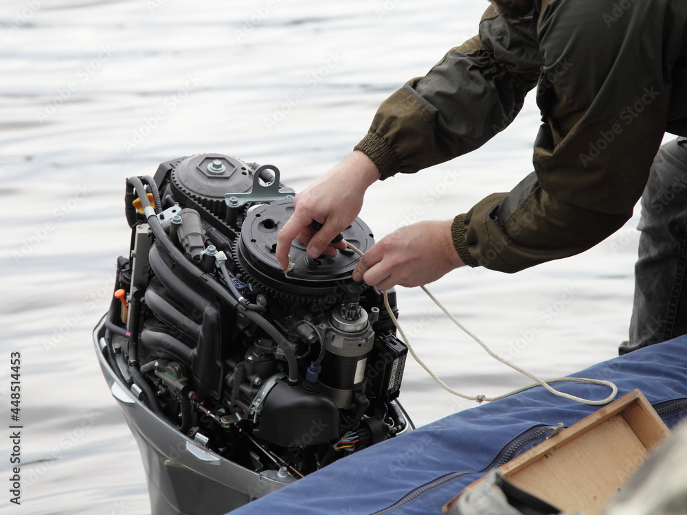 Boater hand start an broken outboard boat motor without the hood cap on the transom of the boat, emergency engine start with rope