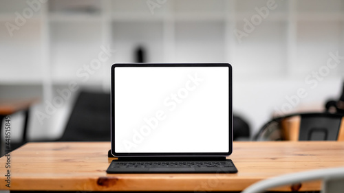 Computer tablet with blank white screen on wooden workspace