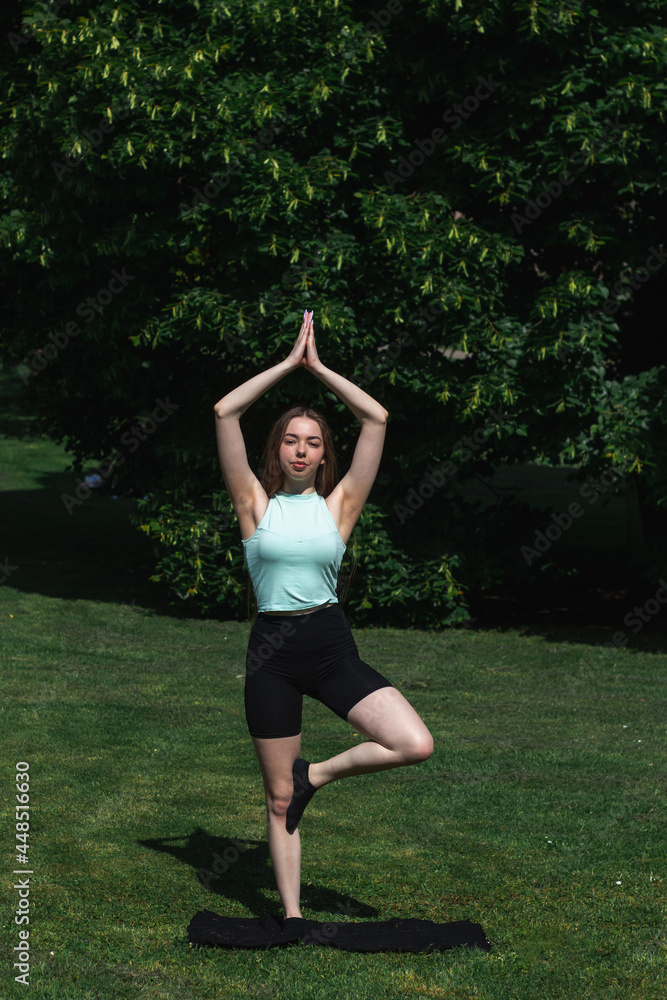 Young caucasian long-haired woman in sportswear is doing yoga in the park. Outdoor workout. Yoga poses Young caucasian long-haired woman in sportswear is doing yoga in the park. Outdoor workout. Yoga poses