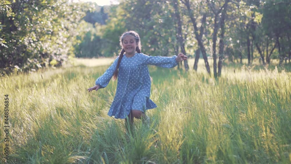 Happy girl. Little girl run through forest park. Kid plays on green grass. Happy kid run in garden. Green grass and trees in forest park. Little girl run through green garden.Happy girl among trees Happy girl. Little girl run through forest park. Kid plays on green grass. Happy kid run in garden. Green grass and trees in forest park. Little girl run through green garden.Happy girl among trees