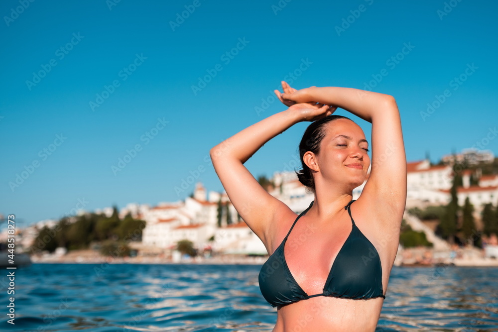 a beautiful woman in a swimsuit posing in the sea at sunset