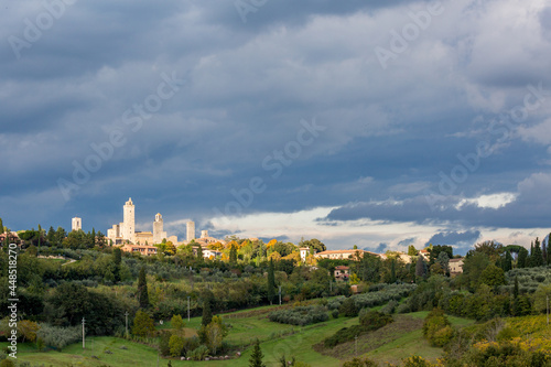 Sun shining selectively only upon the old stone buildings of the city. Tuscany, Italy in the autumn, colorful low angle view, dramatic sky before storm