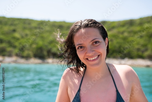 Beautiful woman in green bikini on tropical beach. Portrait of happy young woman smiling at sea. Brunette tanned girl in swimwear enjoying on beach.