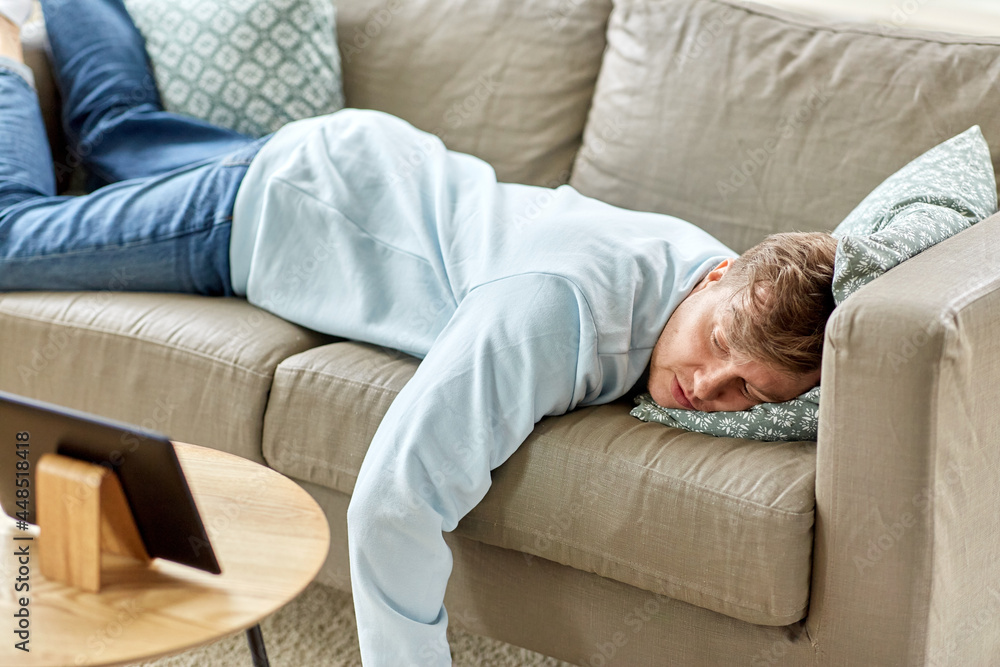 people, boredom and depression concept - bored or lazy young man with tablet pc computer lying on sofa at home people, boredom and depression concept - bored or lazy young man with tablet pc computer lying on sofa at home