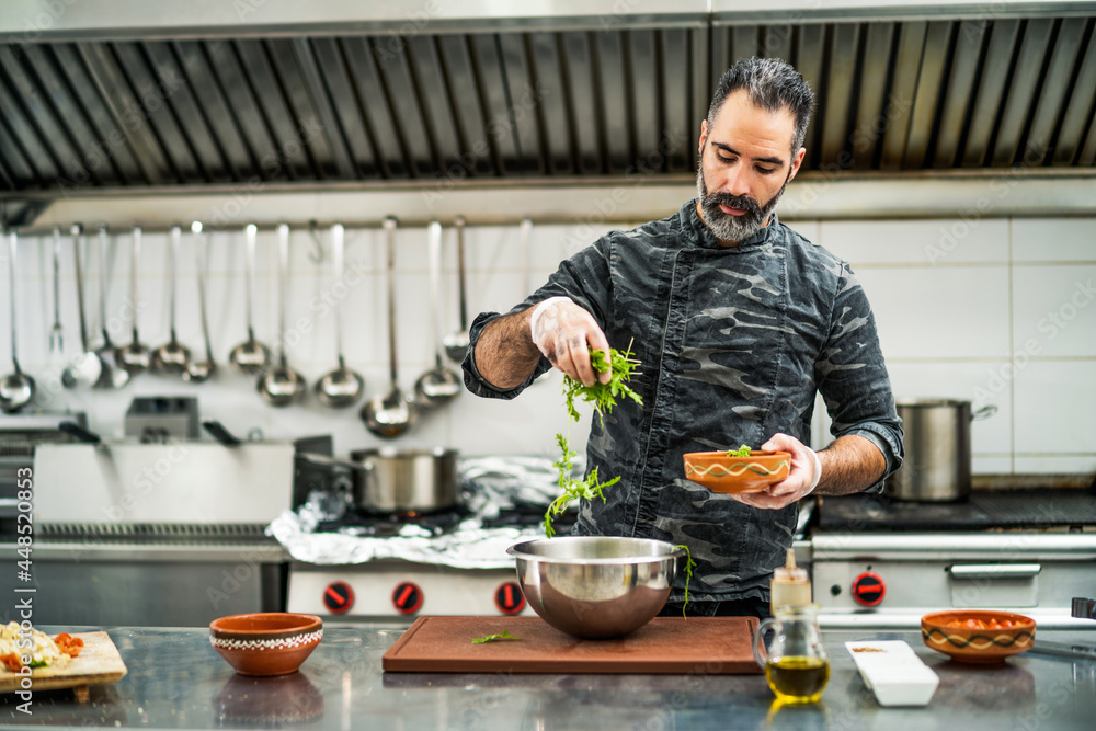 Professional cook is preparing meal in restaurant's kitchen. He is making salad. Professional cook is preparing meal in restaurant's kitchen. He is making salad.