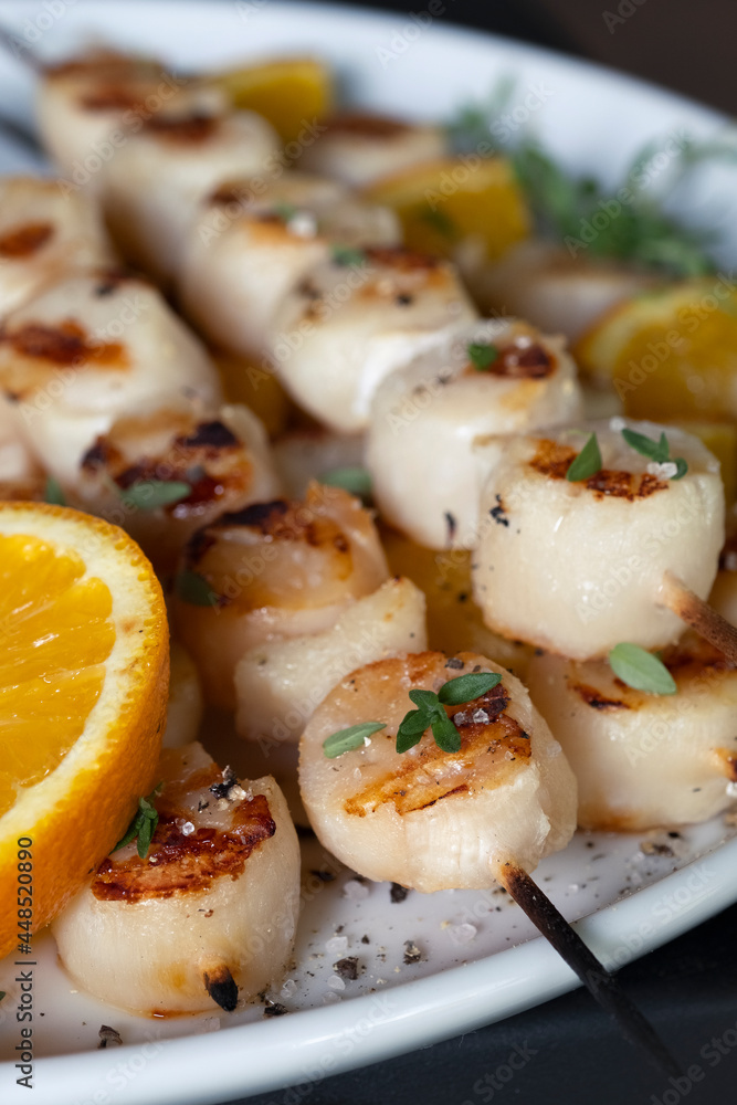 Grilled scallops on wooden skewers with orange and fresh thyme. Grilled scallops on wooden skewers with orange and fresh thyme.