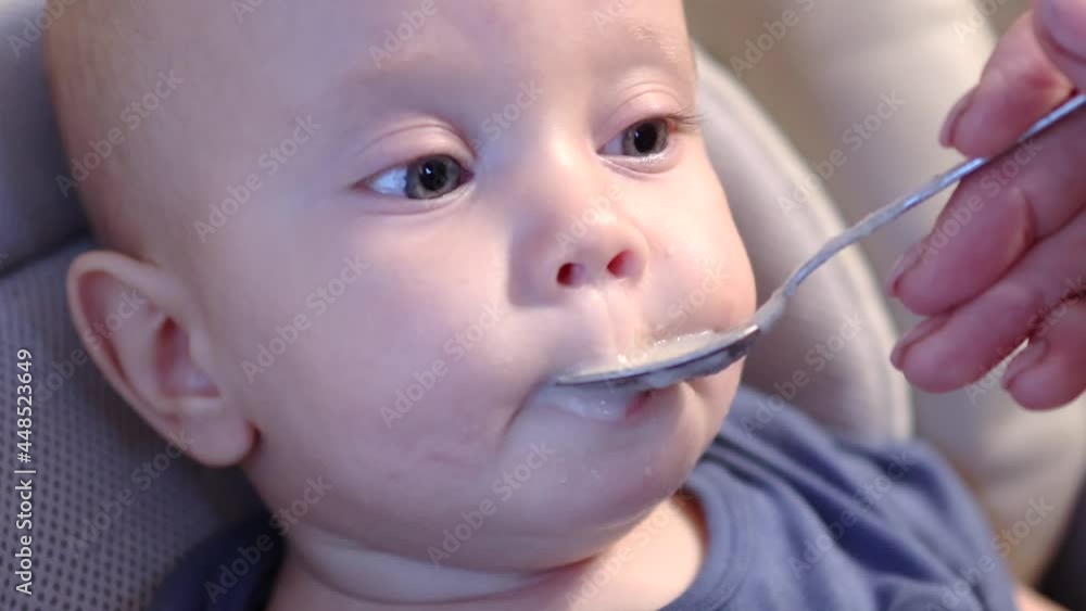 cute face of baby infant tasting food for the first time with spoon and puree mash porridge. baby infant nutrition concept cute face of baby infant tasting food for the first time with spoon and puree mash porridge. baby infant nutrition concept