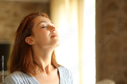 Redhead woman breathing fresh air at home