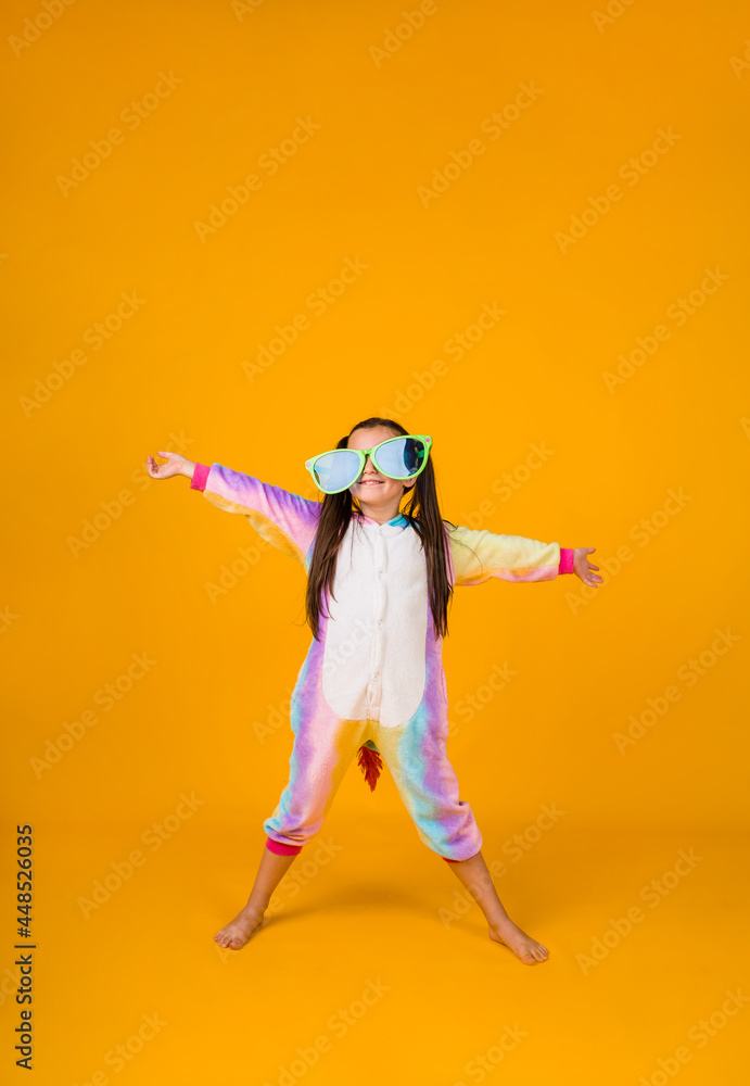 a happy little girl in a plush suit and big glasses on a yellow background with a place for text a happy little girl in a plush suit and big glasses on a yellow background with a place for text
