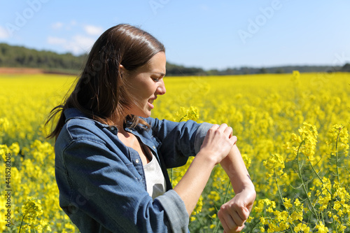 Woman scratching arm in a field on summer photo