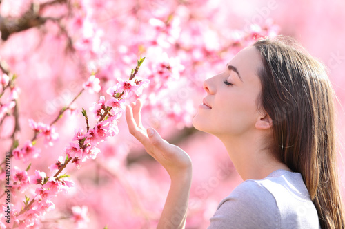 Profile of a woman smelling flowers in a pink field