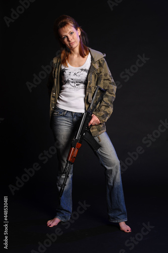 blonde woman in camouflage with arms on a dark background with studio