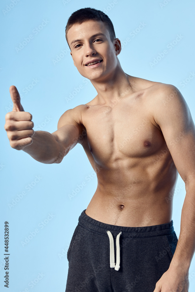 Fototapeta premium nude athlete showing thumb and shorts blue background Model