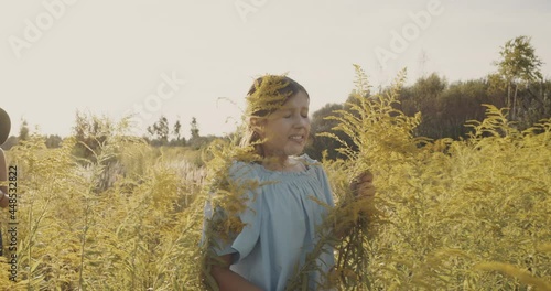 Mother and daughter, walk on a yellow summer lawn under the sun, non urban scene. Girl sneezing in a field of flowers. Pollen allergy concept. Nature background, weekend out of city