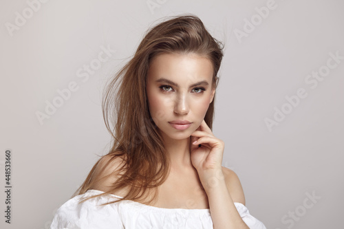 Seductive woman touches cheek looking at camera in studio