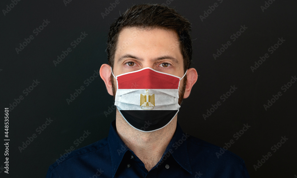 Man wearing Egyptian flag protective medical face mask. He looks worried and concerned. Coronavirus concept in Egypt with black background. Man wearing Egyptian flag protective medical face mask. He looks worried and concerned. Coronavirus concept in Egypt with black background.