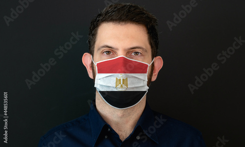 Man wearing Egyptian flag protective medical face mask. He looks worried and concerned. Coronavirus concept in Egypt with black background.