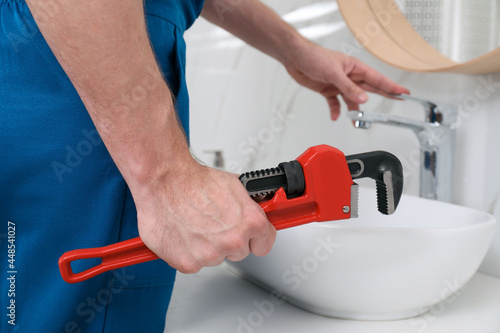 Professional plumber fixing water tap in bathroom, closeup