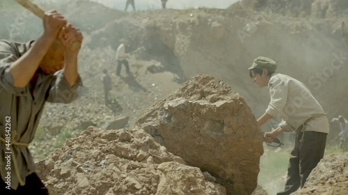 Young miner boy is working in a quarry . Group of many workers are mining with pickaxe in a quarry . Scenic shot in vintage style with artists . Shot on RED EPIC Cinema Camera in slow motion.