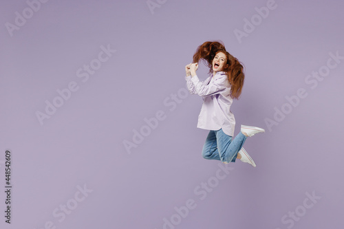 Full size body length side view dizzy crazy amusing young redhead curly green-eyed woman 20s wears white T-shirt violet jacket jumping isolated on pastel purple color wall background studio portrait.