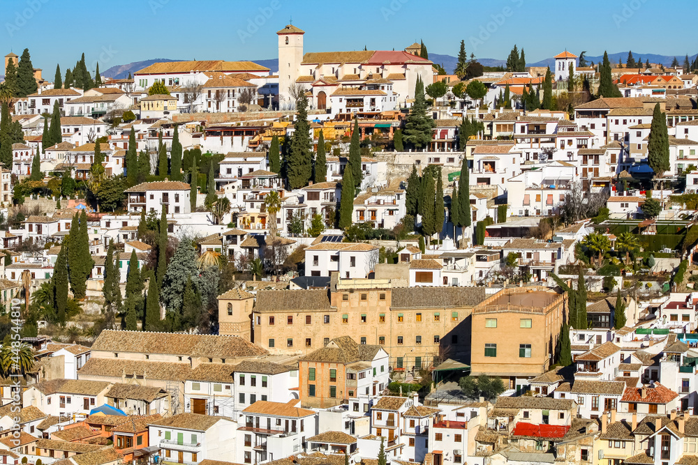 Old houses on a hillside with their roofs and trees. Albaicin Granada.