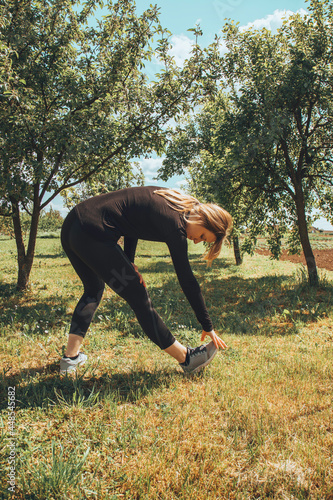 Young woman in sportswear doing exercises in nature. Healthy lifestyle concept.