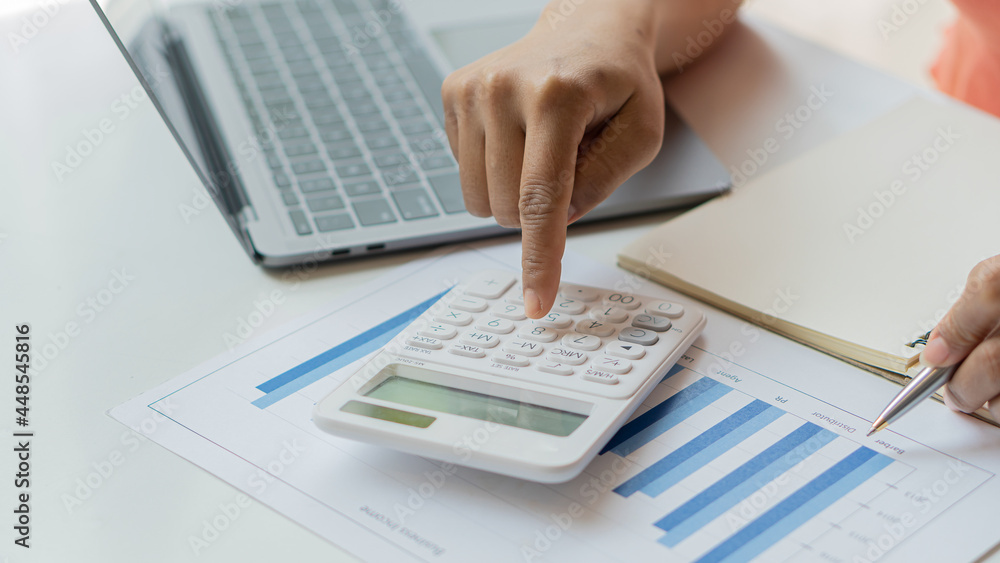 Accountant using computer with clamp and graph document, business man working on desk using calculator to calculate numbers, financial accounting concepts. Accountant using computer with clamp and graph document, business man working on desk using calculator to calculate numbers, financial accounting concepts.