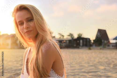 Beautiful young woman on sandy beach, space for text
