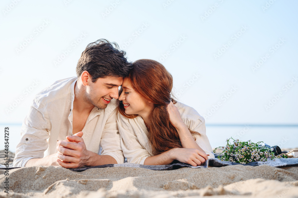Romantic happy smiling young couple two family man woman in white clothes hug lying on picnic plaid rest relax together at sunrise over sea beach ocean outdoor seaside in summer day sunset evening