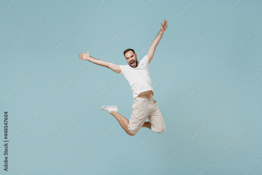 Full length young overjoyed fun joyful happy excited caucasian man 20s wear casual white t-shirt jump high with outstretched hands isolated on plain pastel light blue color background studio portrait Full length young overjoyed fun joyful happy excited caucasian man 20s wear casual white t-shirt jump high with outstretched hands isolated on plain pastel light blue color background studio portrait
