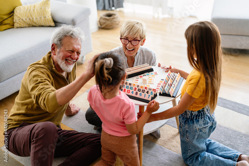 Portrait of happy elderly couple and grandchildren playing together