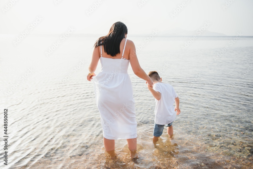 Happy mother and son walk along the ocean beach having great family time on vacation on Pandawa Beach, Bali. Paradise, travel, vacation concept