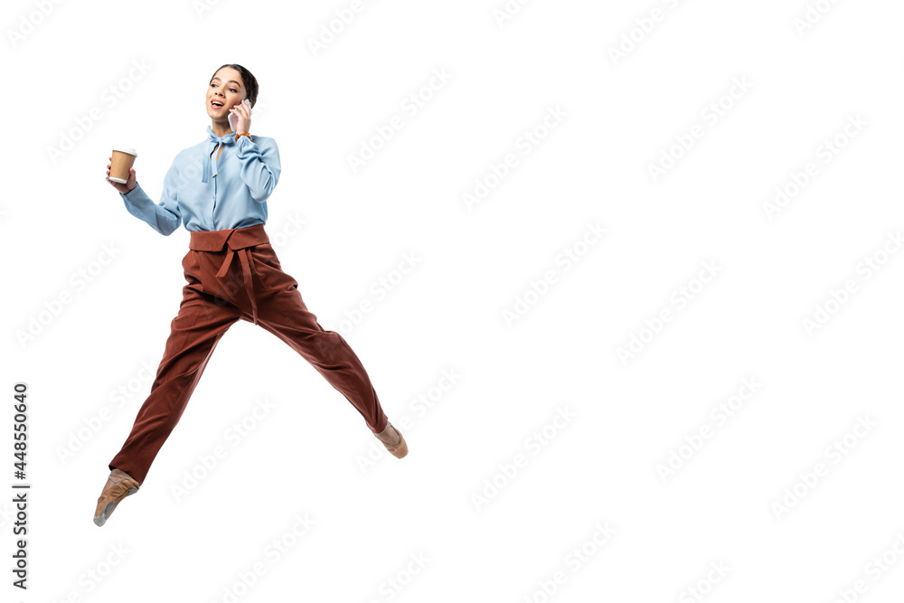 Ballerina with coffee to go talking on mobile phone and jumping isolated on white