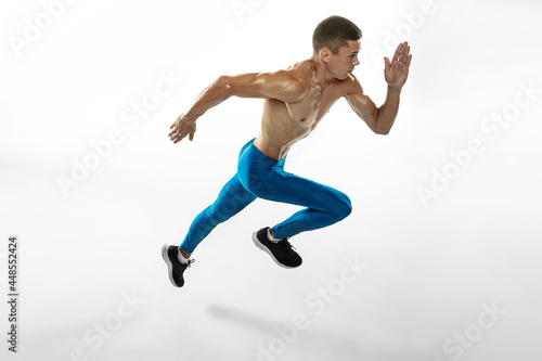 High angle view of young professional male athlete, runner training isolated on white studio background. Muscular, sportive man. Concept of sport, healthy lifestyle