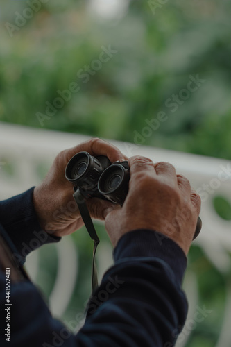 Hands of a man holding binoculars. Close-up image.