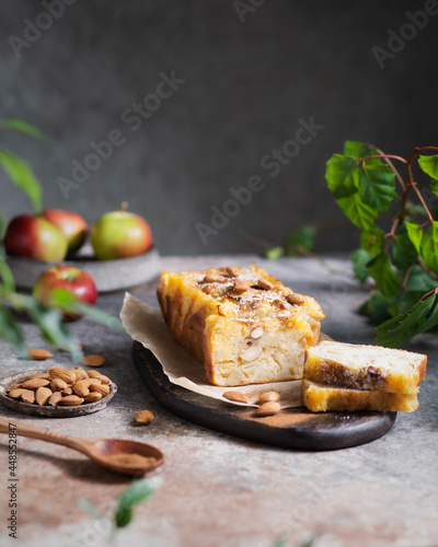 A piece of apple cake with nuts on a plate. Apple dessert on a brown background. Apple pie with hazelnuts and cinnamon. Autumn spicy pastries