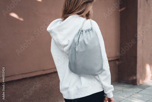 Grey drawstring pack template, mockup of bag for sport shoes on woman's shoulder. photo