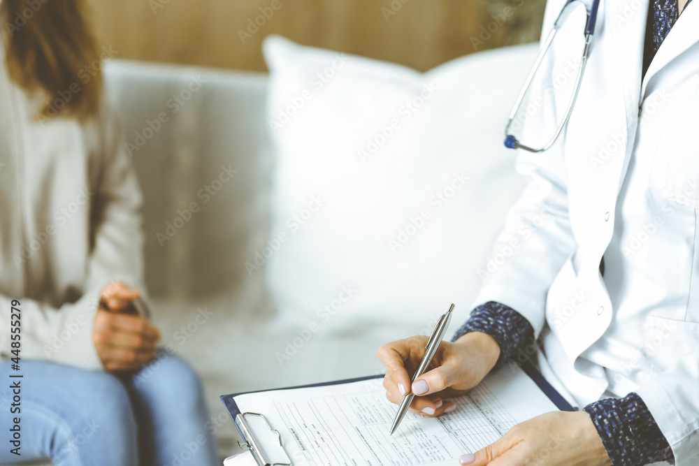 Obraz premium Unknown woman-doctor and patient discussing current health examination while sitting indoors. Stay at home concept during Coronavirus pandemic and self isolation quarantine