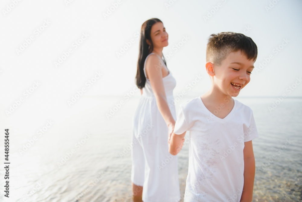 Happy mother and son walk along the ocean beach having great family time on vacation on Pandawa Beach, Bali. Paradise, travel, vacation concept Happy mother and son walk along the ocean beach having great family time on vacation on Pandawa Beach, Bali. Paradise, travel, vacation concept