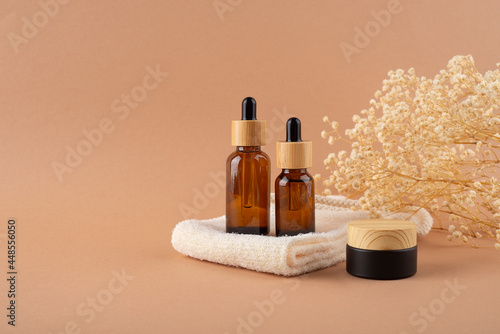 Eco friendly washcloth with amber glass dropper bottle and jars. Zero waste and plastic free concept on beige background with dry plants. Skincare natural cosmetic concept for face body care