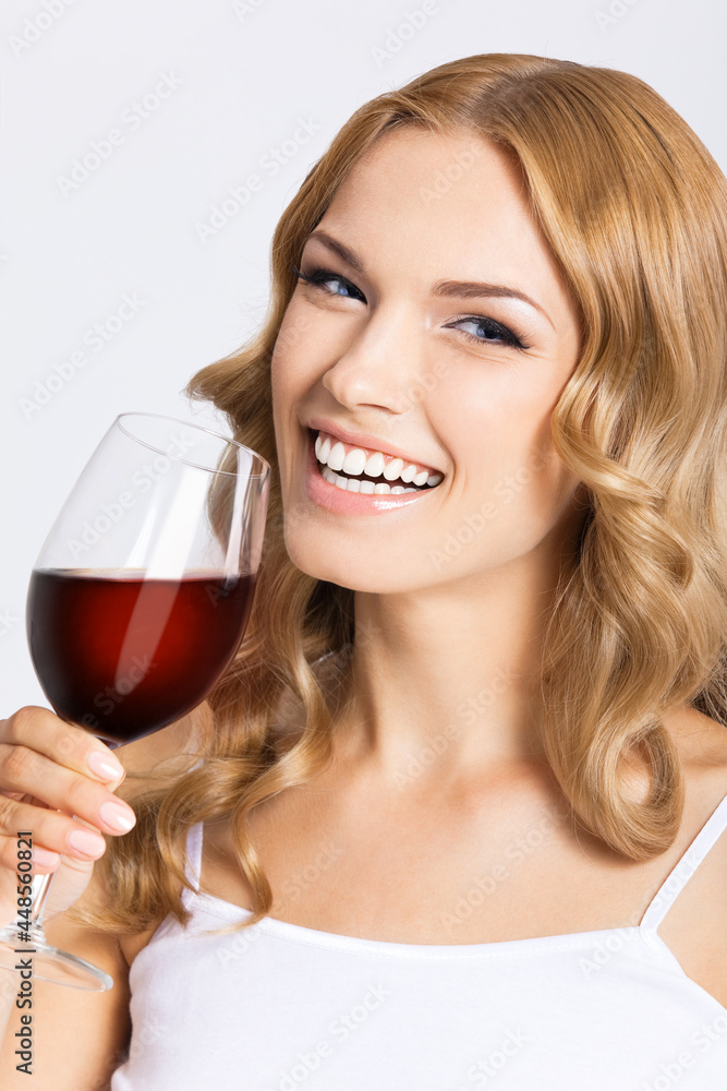 Studio photo of happy smiling woman with glass of red wine, isolated over gray background. Attractive blond girl drinking redwine. Studio photo of happy smiling woman with glass of red wine, isolated over gray background. Attractive blond girl drinking redwine.