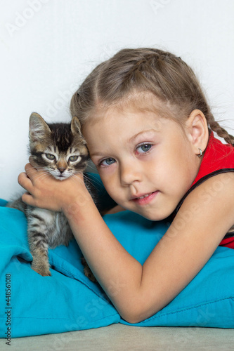 Portrait of cute caucasian girl of five years old holding kitten looking at camera on the white background
