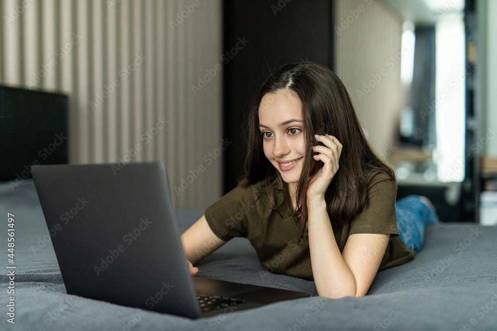 Beautiful young woman lying on bed and using computer laptop for using social media and shopping online relax in cozy bedroom in holiday Beautiful young woman lying on bed and using computer laptop for using social media and shopping online relax in cozy bedroom in holiday