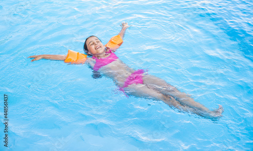Pretty little girl swimming in outdoor pool and have a fun