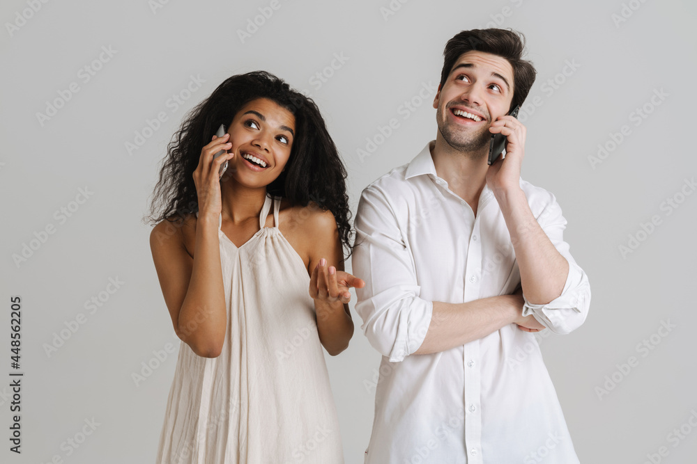 Young multiracial couple smiling while talking on mobile phones Young multiracial couple smiling while talking on mobile phones
