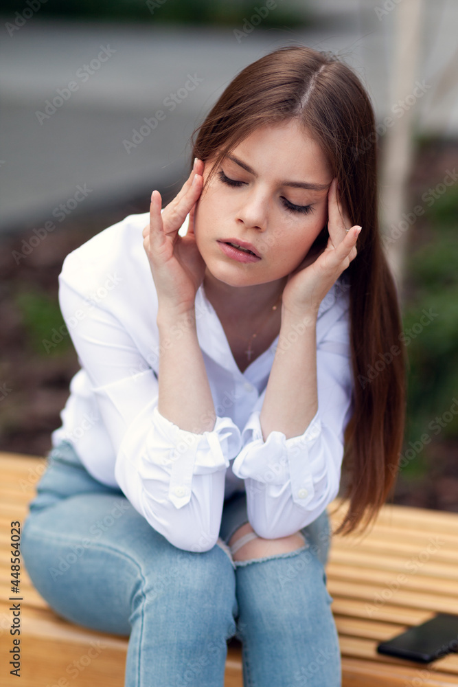 Panic attack. Woman sitting outdoors with headache, negative emotions.