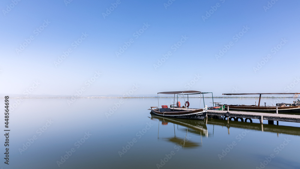 Barcas sobre agua como espejo en laguna de la albufera de Valencia. Azul. Tranquilidad. Paz