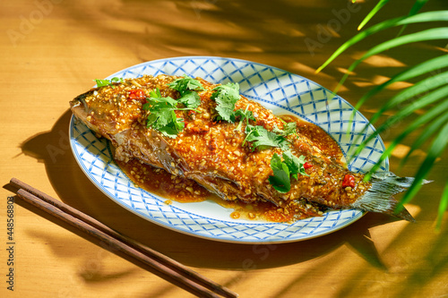 Whole fried carp with hot sauce and Sichuan pepper. Wood background. Chinese cuisine